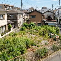 市街地の相続した土地が管理しきれず、雑草などが生えているイメージ、少し俯瞰して見下ろした様子